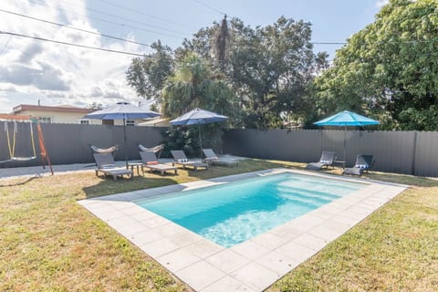 Private fenced pool area with loungers, umbrellas, and hammocks