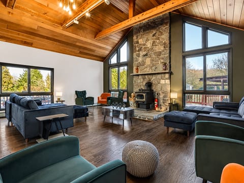 Vaulted-ceiling great room with stone fireplace and bright forest views