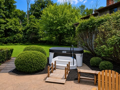 Private backyard hot tub surrounded by lush landscaping and patio space