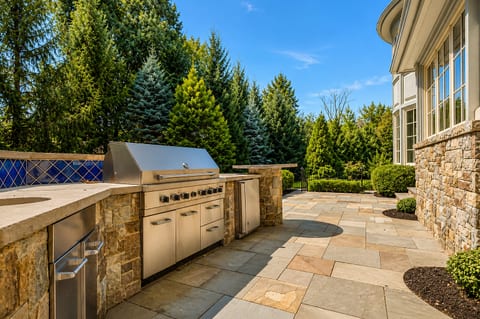 Private stone patio with built-in grill and upscale outdoor entertaining space
