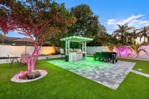 Resort-style backyard with outdoor kitchen, dining patio, and mood lighting