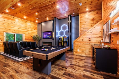Cozy woodsy game room with pool table, arcade games, fireplace & TV