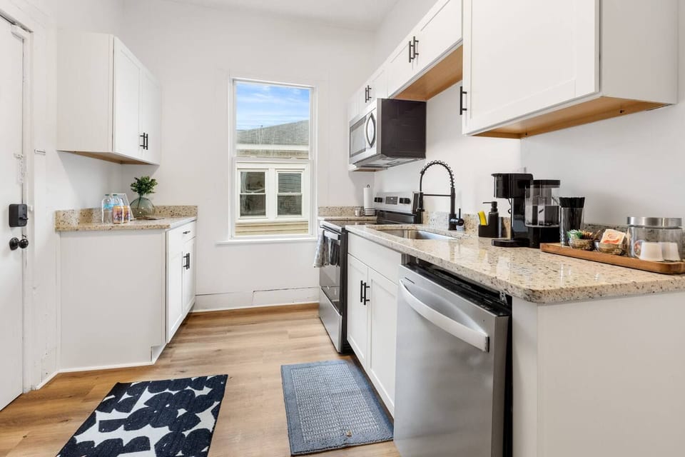 Bright modern kitchen with granite counters, stainless appliances & coffee bar