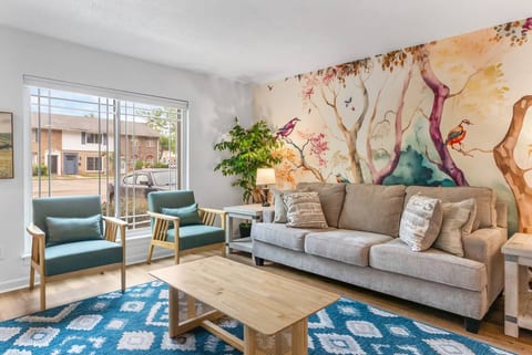 Bright living room with bold mural, cozy seating, and natural light