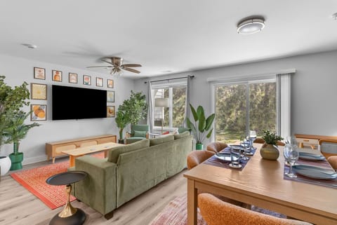 Bright open living-dining space with large TV and patio access