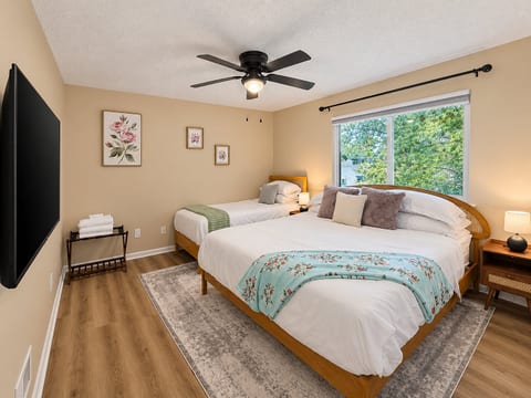Bright family-friendly bedroom with queen, twin, TV, and leafy views