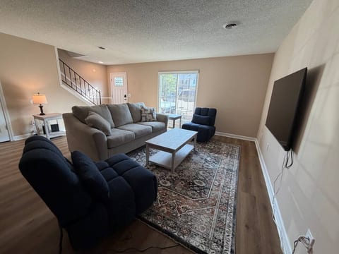 Cozy, sunlit living room with plush seating and a wall-mounted TV