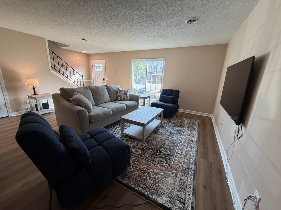 Cozy, sunlit living room with plush seating and a wall-mounted TV
