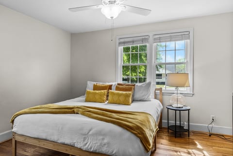 Bright, cozy bedroom with natural light, hardwood floors, and leafy views