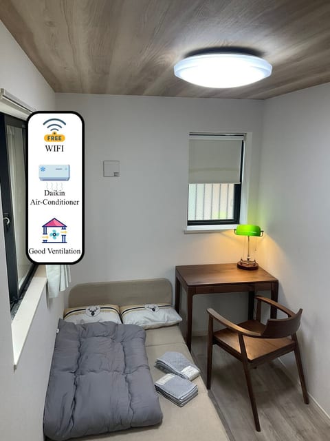 A 100cm-wide sofa bed that can be adjusted to sofa mode. The room features a black walnut desk and chair, paired with a classic green glass lamp. Essentials like a duvet, hairdryer, and USB charging cable are also provided.
