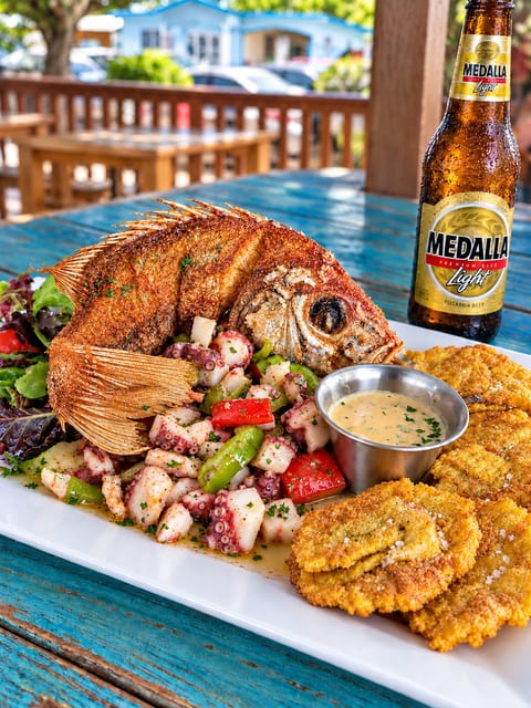 Tropical patio dining with whole fried fish, tostones, and cold local beer