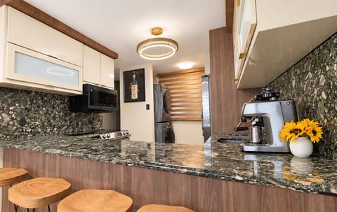 Modern kitchen with stone countertops, breakfast bar, and coffee station
