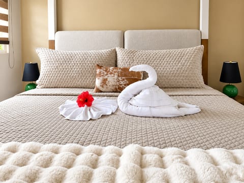 Unwind in a cozy king bed with soft linens, a plush throw, and thoughtful towel artistry for a welcoming island stay.