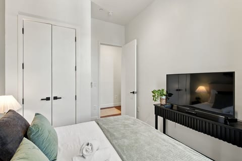 Bright modern bedroom with TV, high ceilings, and sleek minimalist style