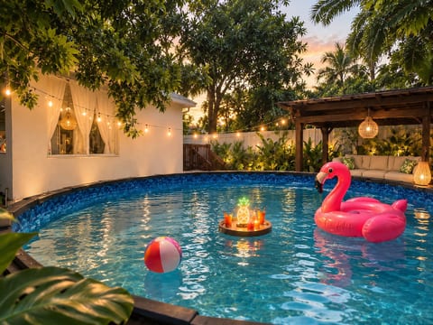 Tropical backyard pool oasis with sunset lighting and cozy lounge seating