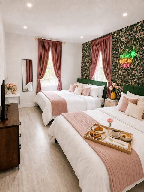 Chic double-queen room with floral wall, neon sign, and boutique styling