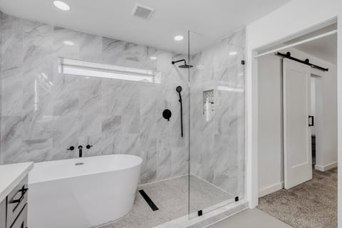 Spa-like bathroom with soaking tub, glass shower, and elegant marble tile