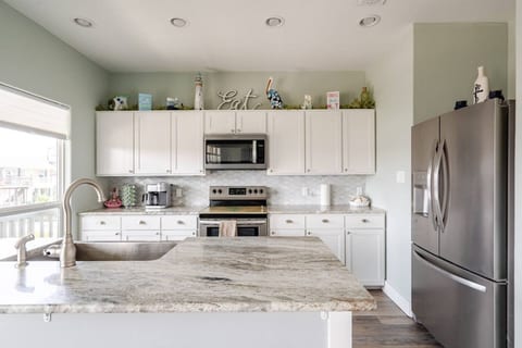 White kitchen with a granite island and farmhouse sink