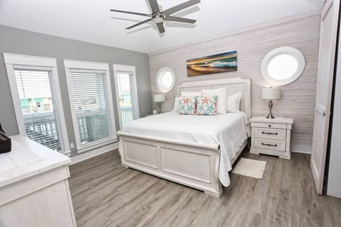 King bedroom with porthole windows and shiplap walls