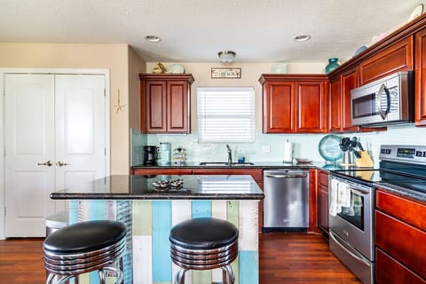 Full kitchen with a granite island, bar stools and stainless appliances