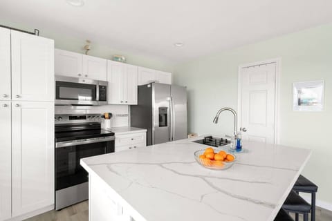 White kitchen with a quartz island and stainless appliances