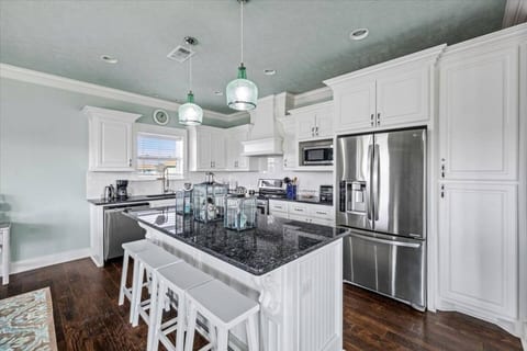 White kitchen with granite counters and an island with bar stools
