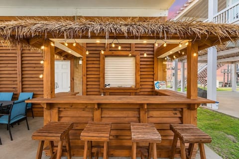 Thatched tiki bar with string lights and bar stools
