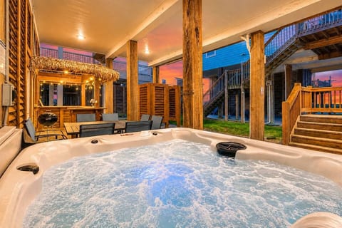 Bubbling hot tub under the house, with the tiki bar lit up at sunset