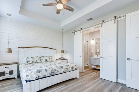 King bedroom with a shiplap wall and barn doors to the bath