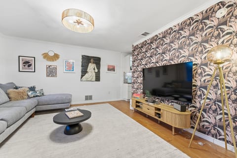 Stylish lounge with sectional, big TV & chic wallpaper accent