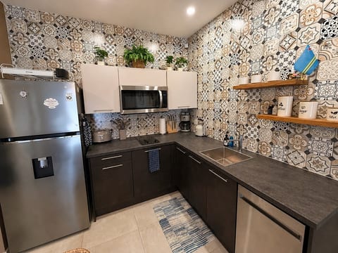 Kitchen with cooktop, refrigerator/freezer, microwave, dishwasher, cookware and coffee-making equipment.