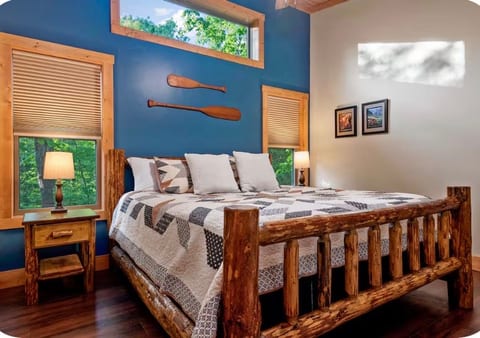 Cozy cabin-style bedroom with rustic log bed and serene wooded views