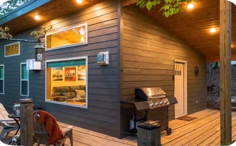 Cozy modern cabin with spacious deck, warm lighting, and grill