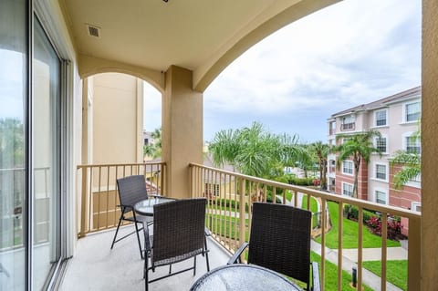 Balcony with 4 chairs and two small tables. Can see a small part of the pool.