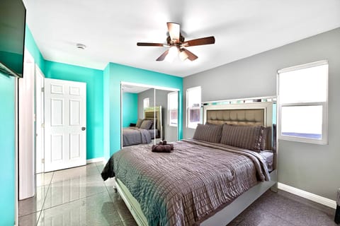 Bright king suite with ceiling fan, mirrored closet, and sleek tile floors