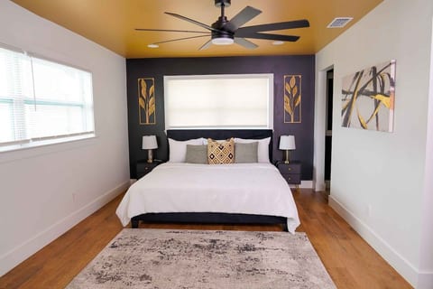 Spacious primary suite with a king-size bed, overhead ceiling fan, and bedside reading lamps.