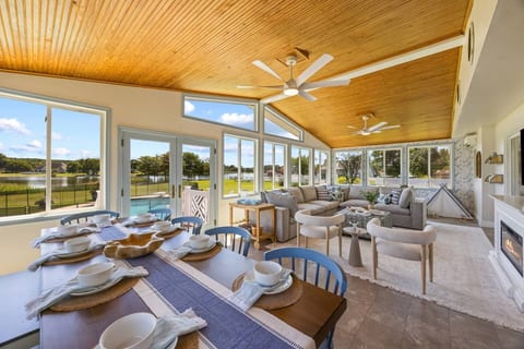 Cathedral ceilings with natural wood light-up this waterfront living room. This room has a dining table for 10, sofa area with electric fireplace and 65" tv and the children's playroom.