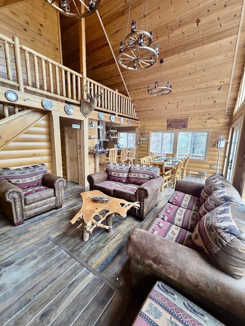 Large living and dining area with a glass front, 20 foot tall ceiling and a wood burning fireplace.
The wagon wheel chandeliers are made by my father.