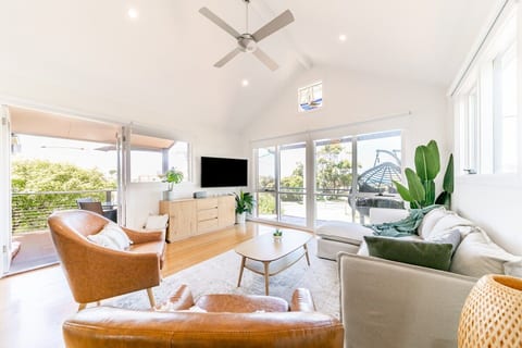 Living area with wall mounted 55” smart TV. Adjustable arm means you can change the viewing angle to suit you… or the person cooking in the kitchen!! Also shows the access to the balcony, outdoor dining area and BBQ.