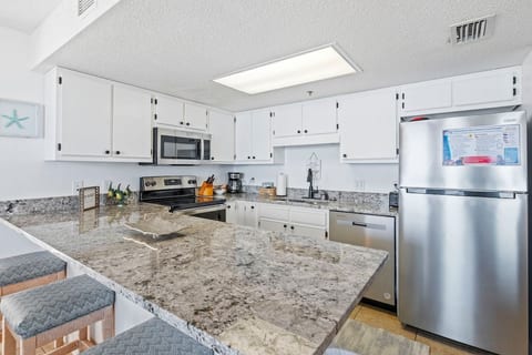 Spread out on the granite and actually cook — full-size range, dishwasher, and a bar for whoever wanders in first.