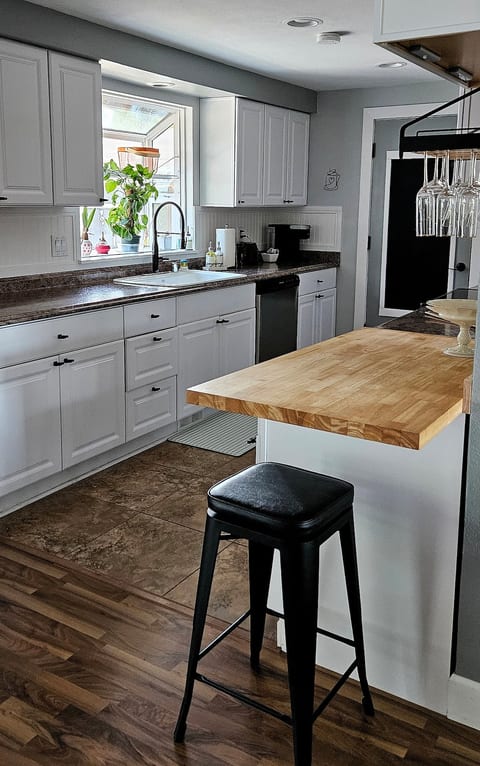 Fully stocked kitchen & small bar area • Natural light • Farmhouse style sink • Plants  • Butcher block tops • Plenty of counter space • Under-counter refrigerator  • Oven  • Dishwasher  • Coffee  • Toaster  • Air-fryer  • Pots • Pans • Utensils.