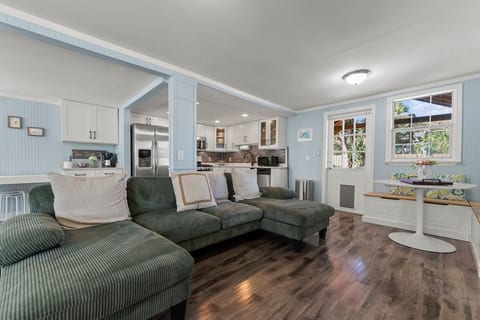 Our cozy open-concept living room features a TV, board games, books, and coastal oyster wallpaper, creating a relaxing space to unwind, watch a movie, read, or enjoy game night with family and friends.