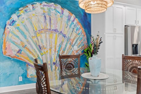 tunning large calico shell art & vibrant colors create a lively ambiance. Cozy seating for four under a beautiful rattan chandelier ensures stylish, inviting meals.