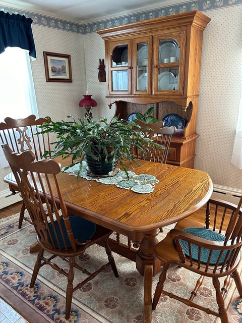 A warm and inviting dining space with classic wooden furniture, ideal for family meals or casual dining. The traditional décor, including a china cabinet and floral accents, adds a homey touch.