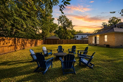 Spacious fenced backyard with fire pit seating under a sunset sky