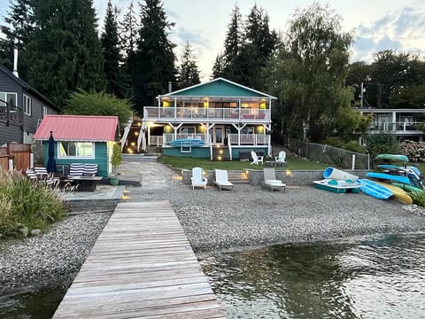 View of house, boat house, kayaks, canoe, paddle boat, paddle boards from the dock.