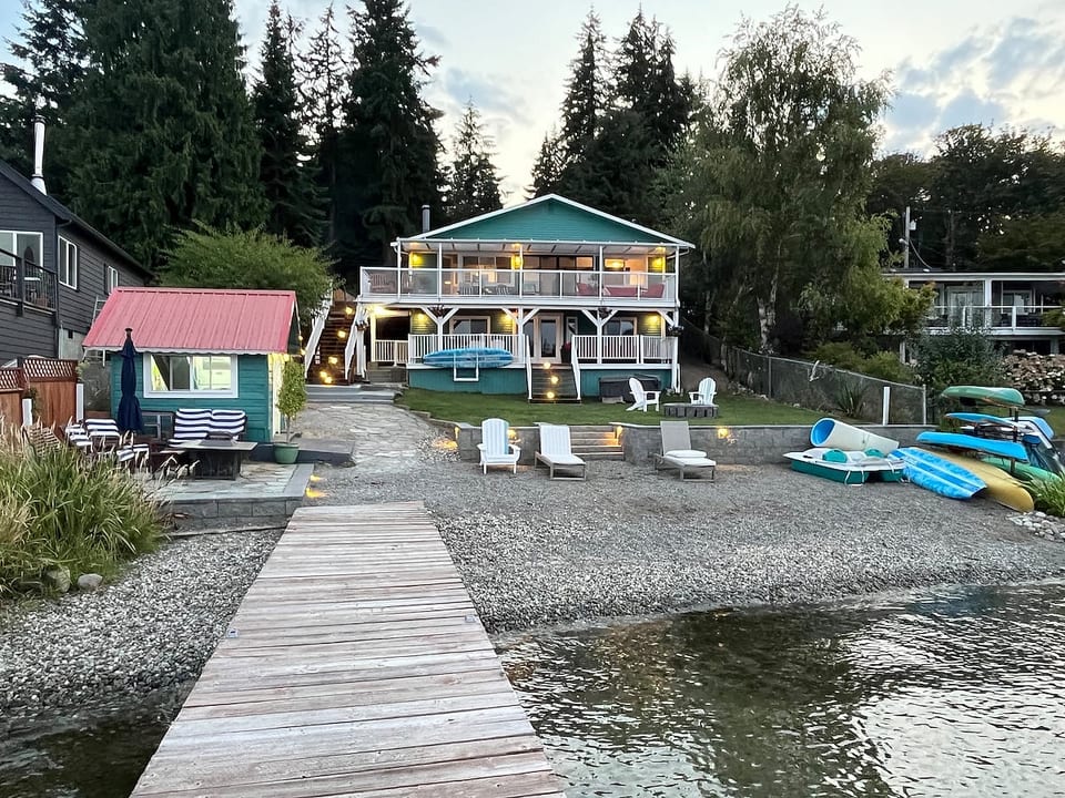 View of house, boat house, kayaks, canoe, paddle boat, paddle boards from the dock.
