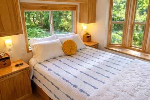 Main-floor bedroom with a queen bed and forest views on two sides