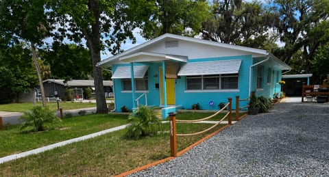 Cheerful coastal cottage with yellow door, roomy drive, and shady yard