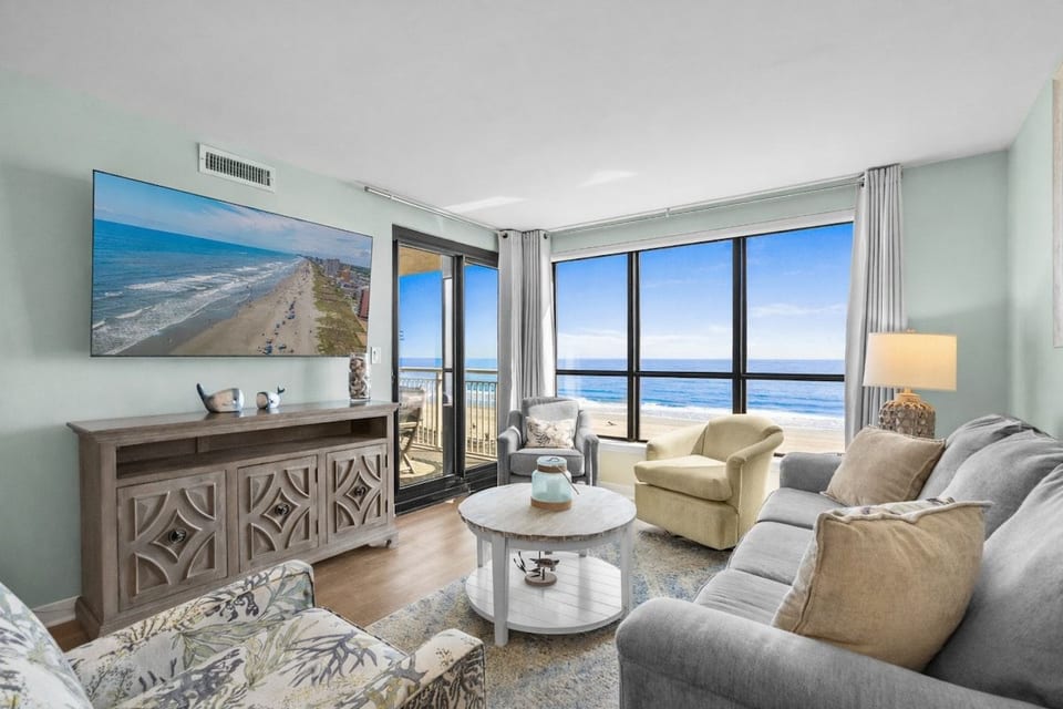 Living area features a Smart TV, ample seating, direct balcony access, and amazing Atlantic Ocean views.